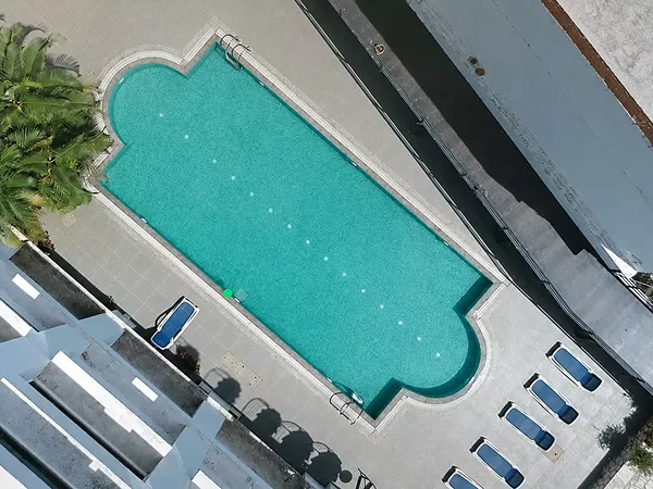 Outdoor hotel swimming pool with sun loungers and hill views